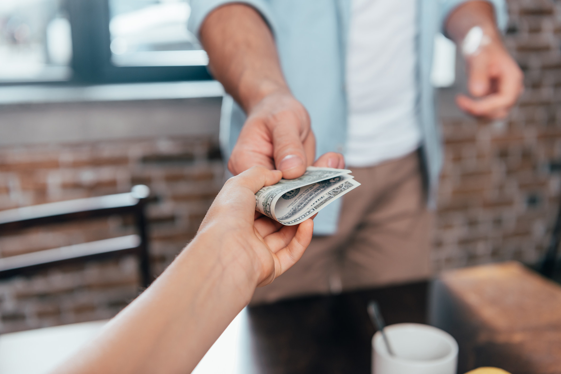 a person handing folded money to someone else