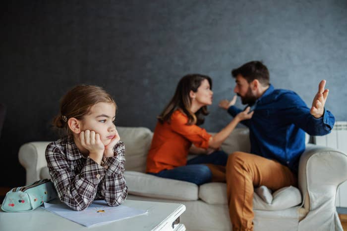 A child sitting in front of her parents while they argue on the couch