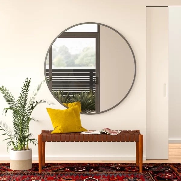 The round mirror over a bench in an entryway