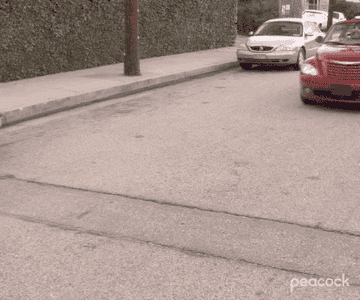 GIF of Michael from &quot;The Office&quot; driving in a red car