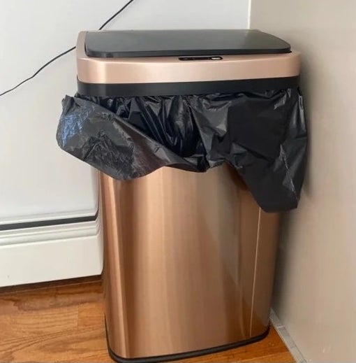 the copper trash can next to a wall