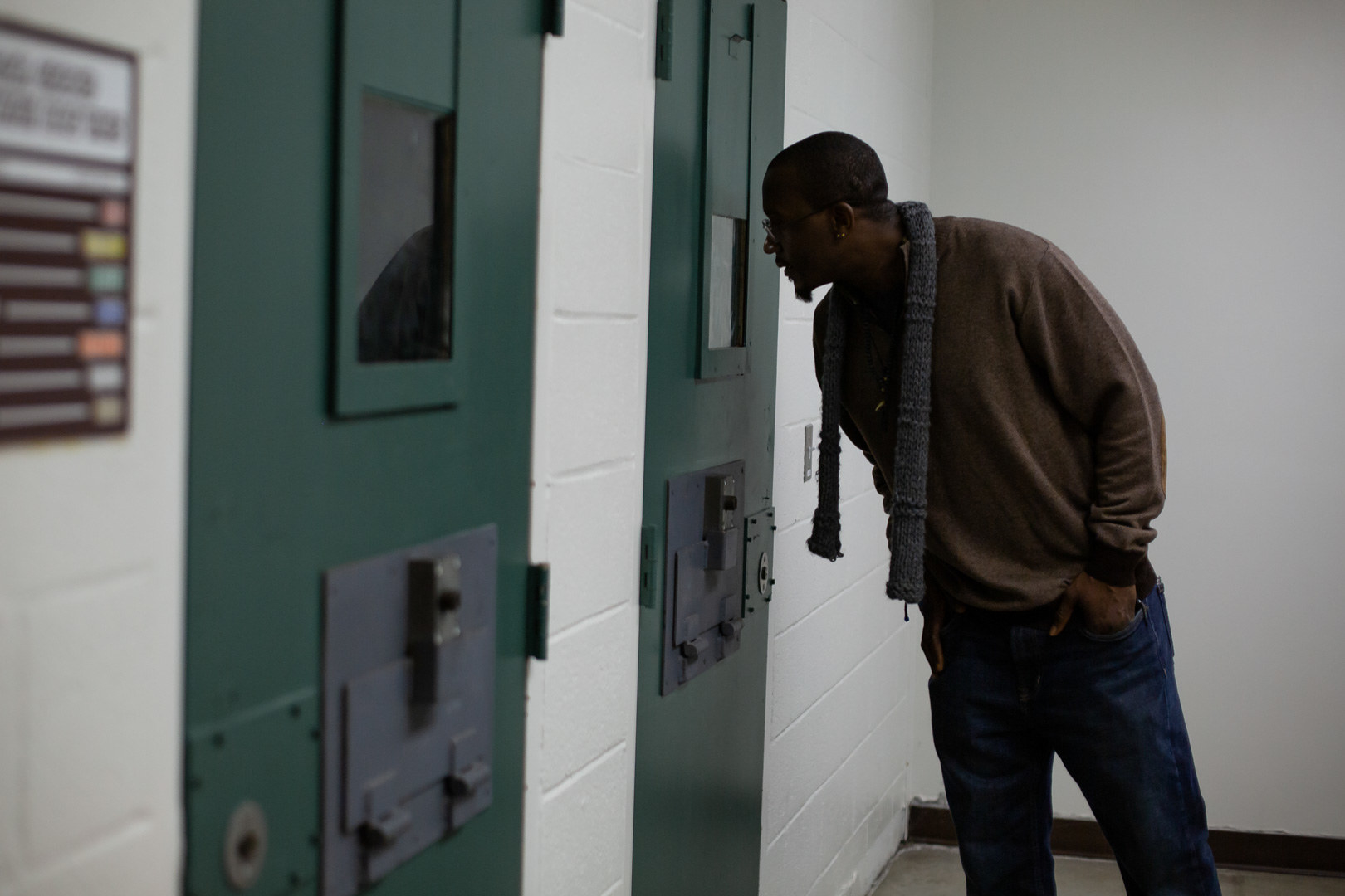 Quinnie looks through the viewing window on a cell door