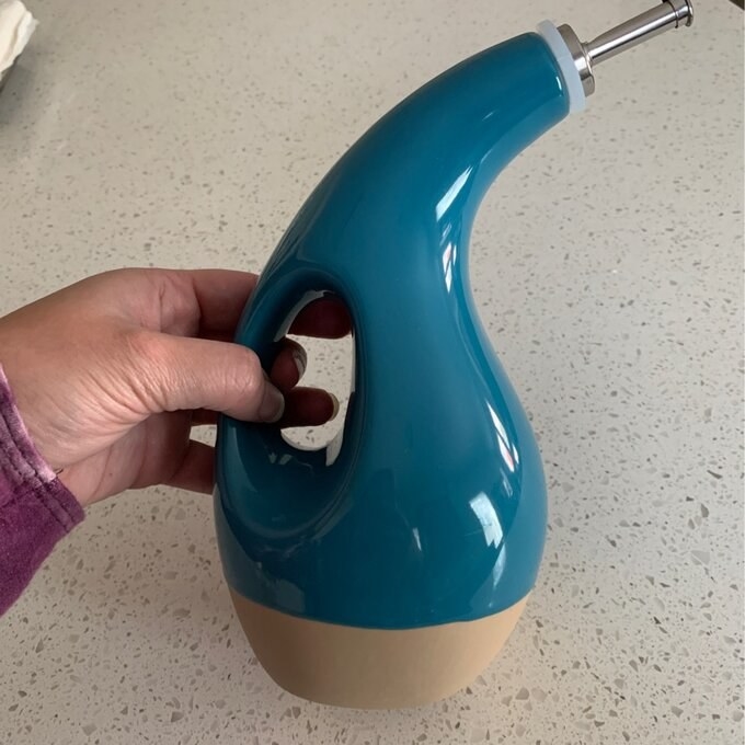 A reviewer&#x27;s image of a blue olive oil dispensing bottle