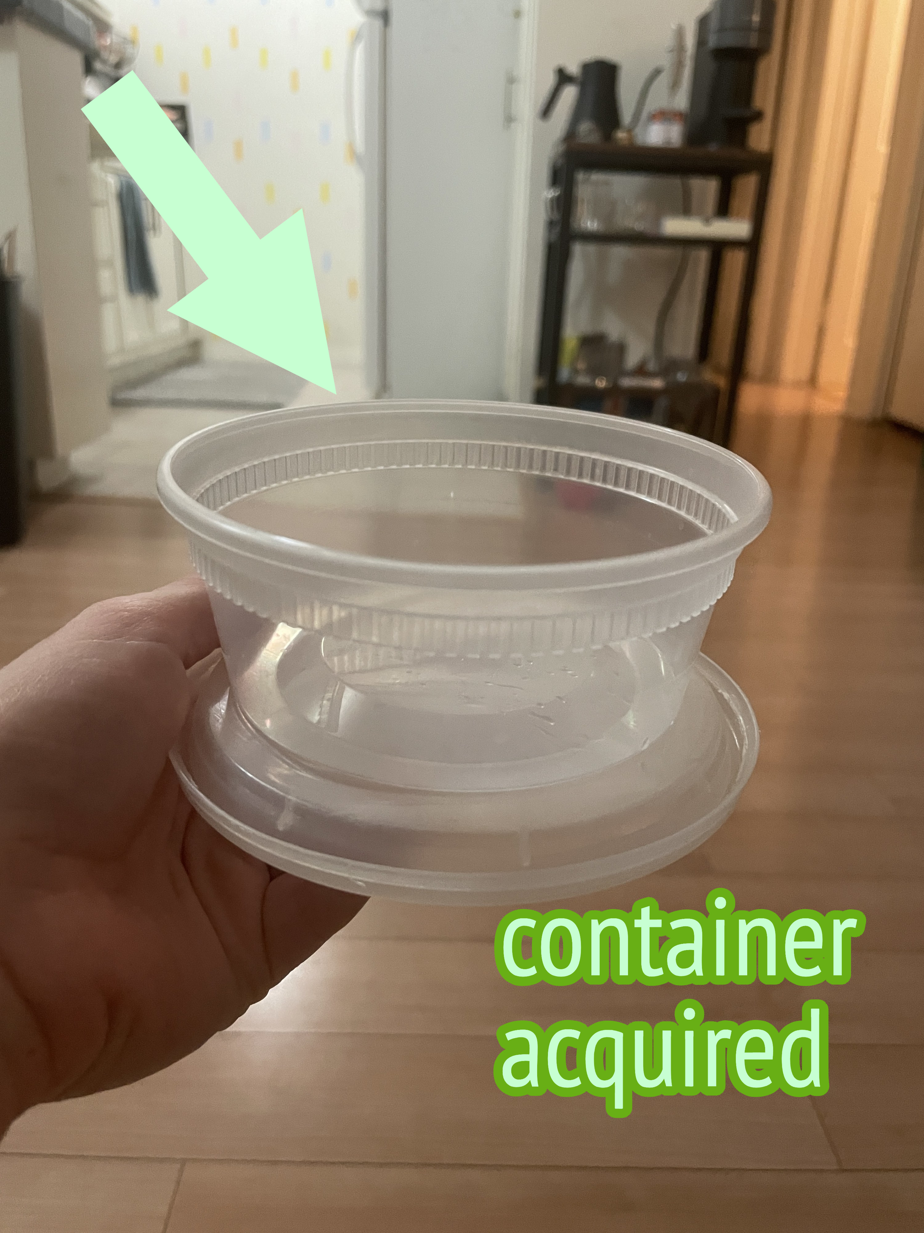 Arrow pointing to plastic container in someone&#x27;s hand, with text &quot;container acquired&quot;