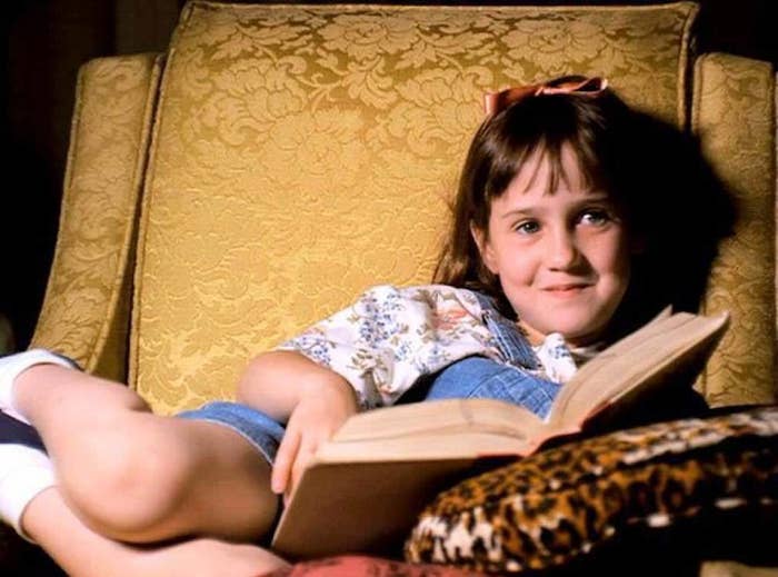 A young girl reading on a couch