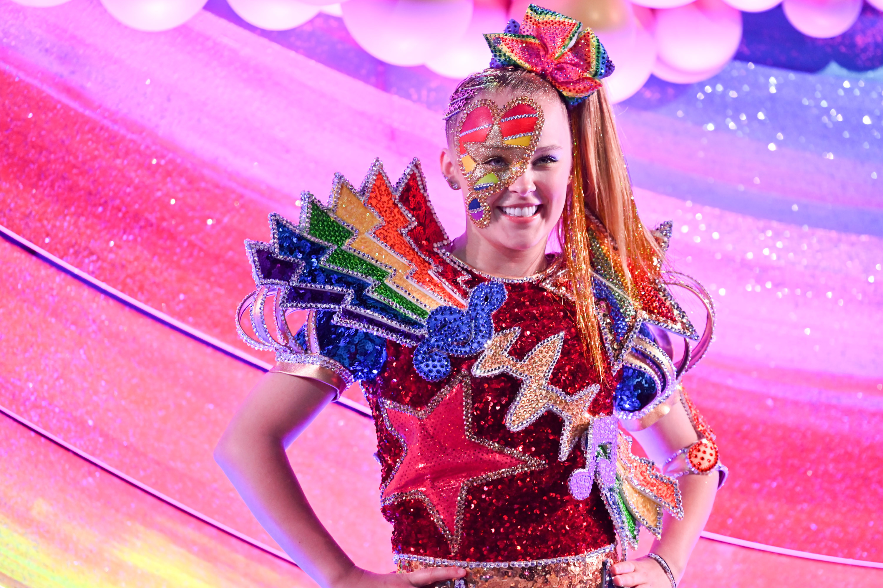 JoJo smiles while wearing a rainbow spangled outfit