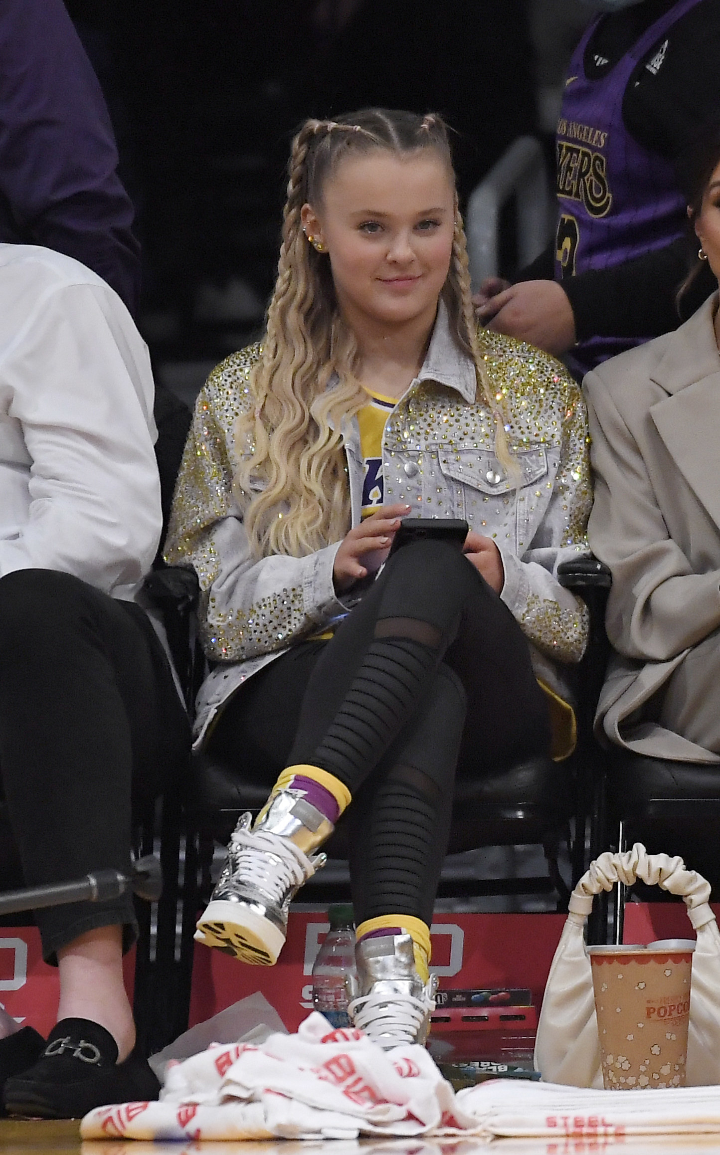 JoJo holds her phone while sitting courtside