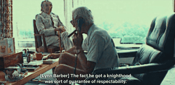 A GIF of Jimmy Savile talking on the phone with a cigar in his mouth