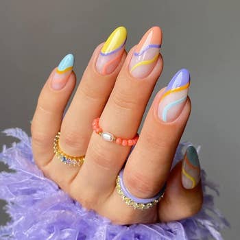 A model wears the purple, orange, yellow, blue and coral swirl set with matching rings