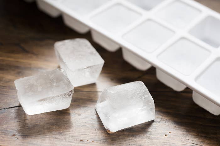 Ice cubes sit on a table next to an ice cube tray
