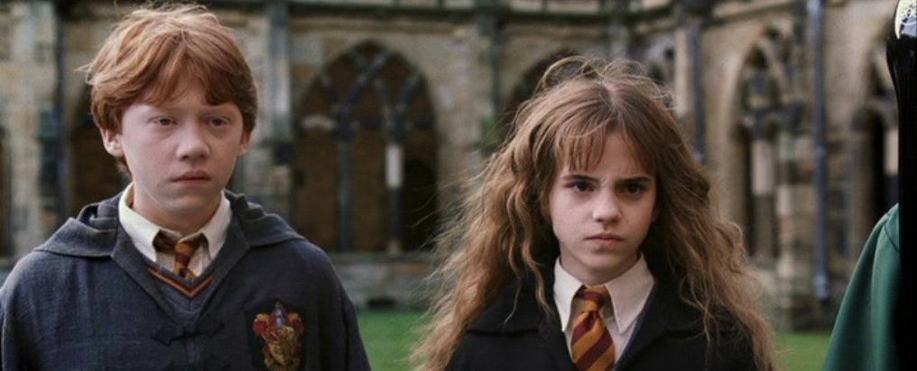 Ron and Hermione standing in the Hogwarts courtyard, looking angry