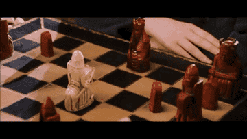 A gif of a red chess piece, the Queen, moving across the board of her own accord and smashing a white knight