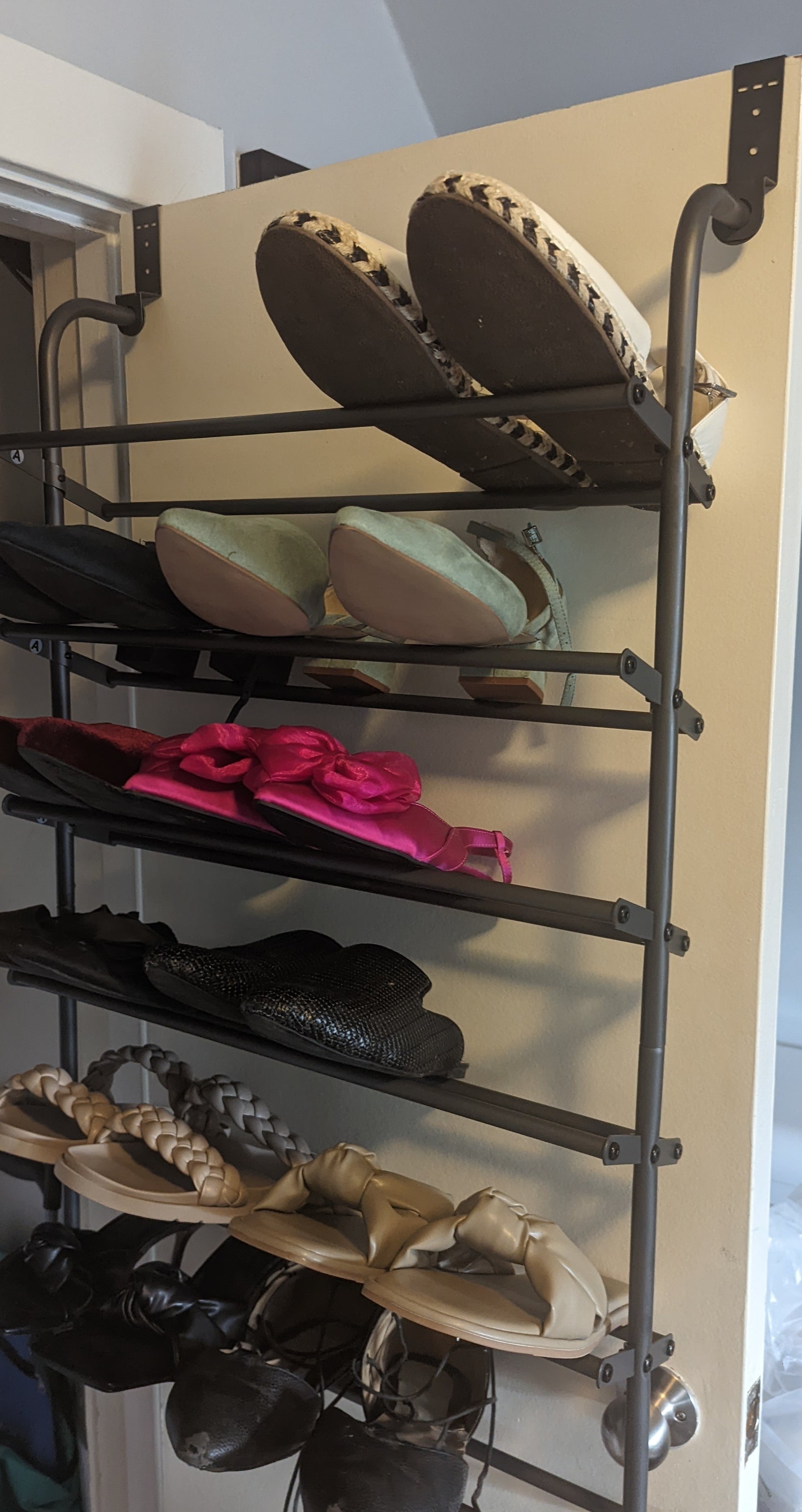 A shoe rack hanging from the door of a closet with tons of shoes on it