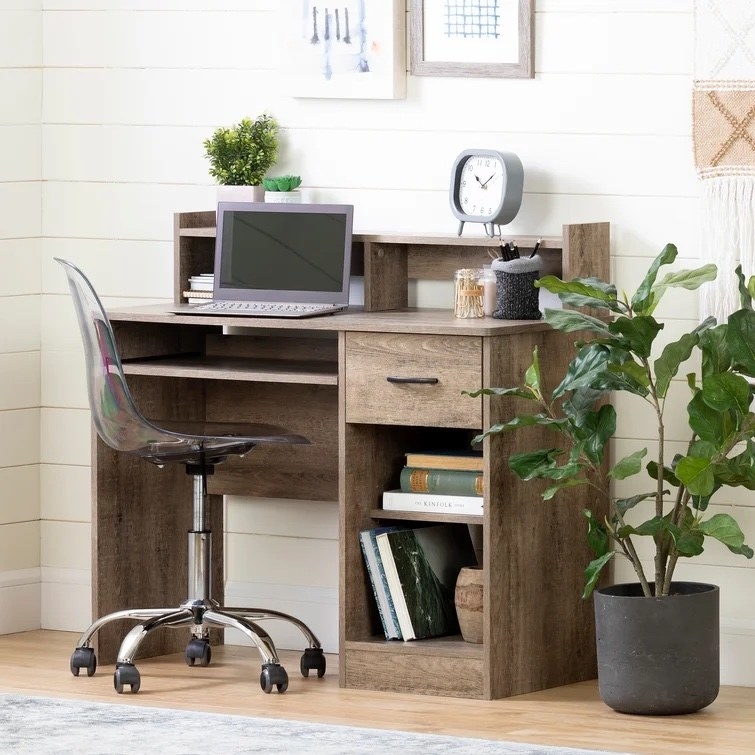 The desk in a room with a computer on it next to a plant