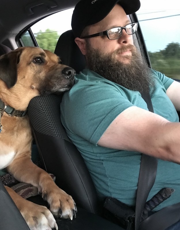 Rusty and his new owner taking a drive while Rusty rests his chin on the driver seat