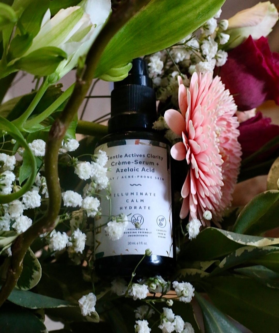 a bottle of the azelaic acid serum tucked into some fresh flowers