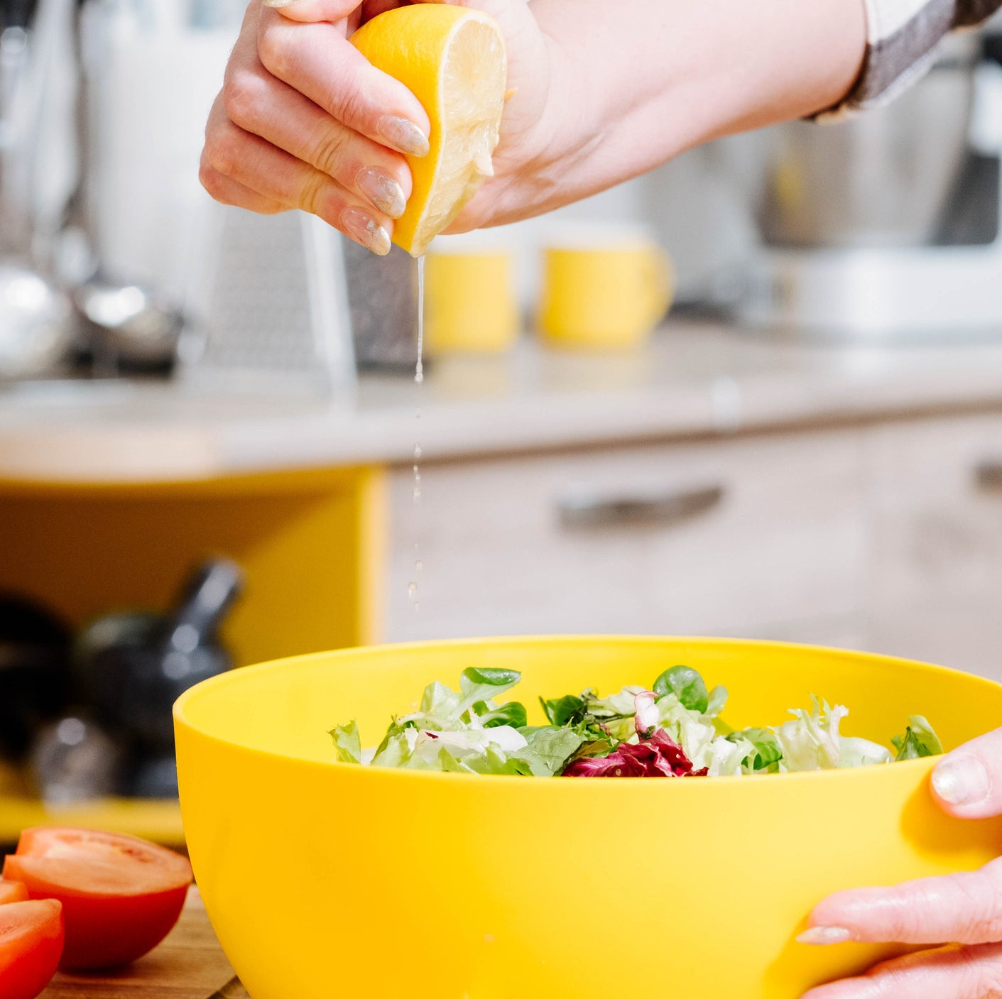 Closeup of female hand squeezing lemon onto a salad