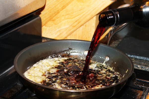 Close-up of red wine being poured into a frying pan