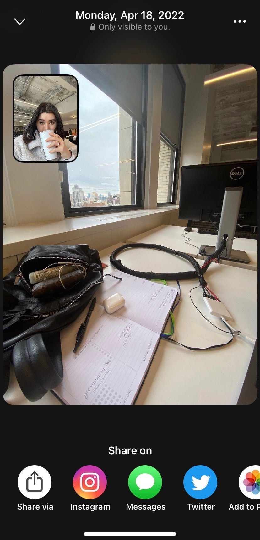 The writer drinking coffee at a table with a computer and an open bag on it