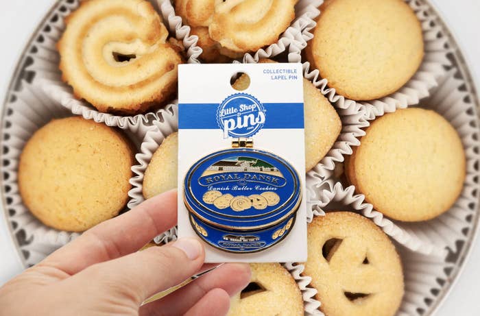 Hand holding Royal Dansk blue tin pin in front of butter cookies
