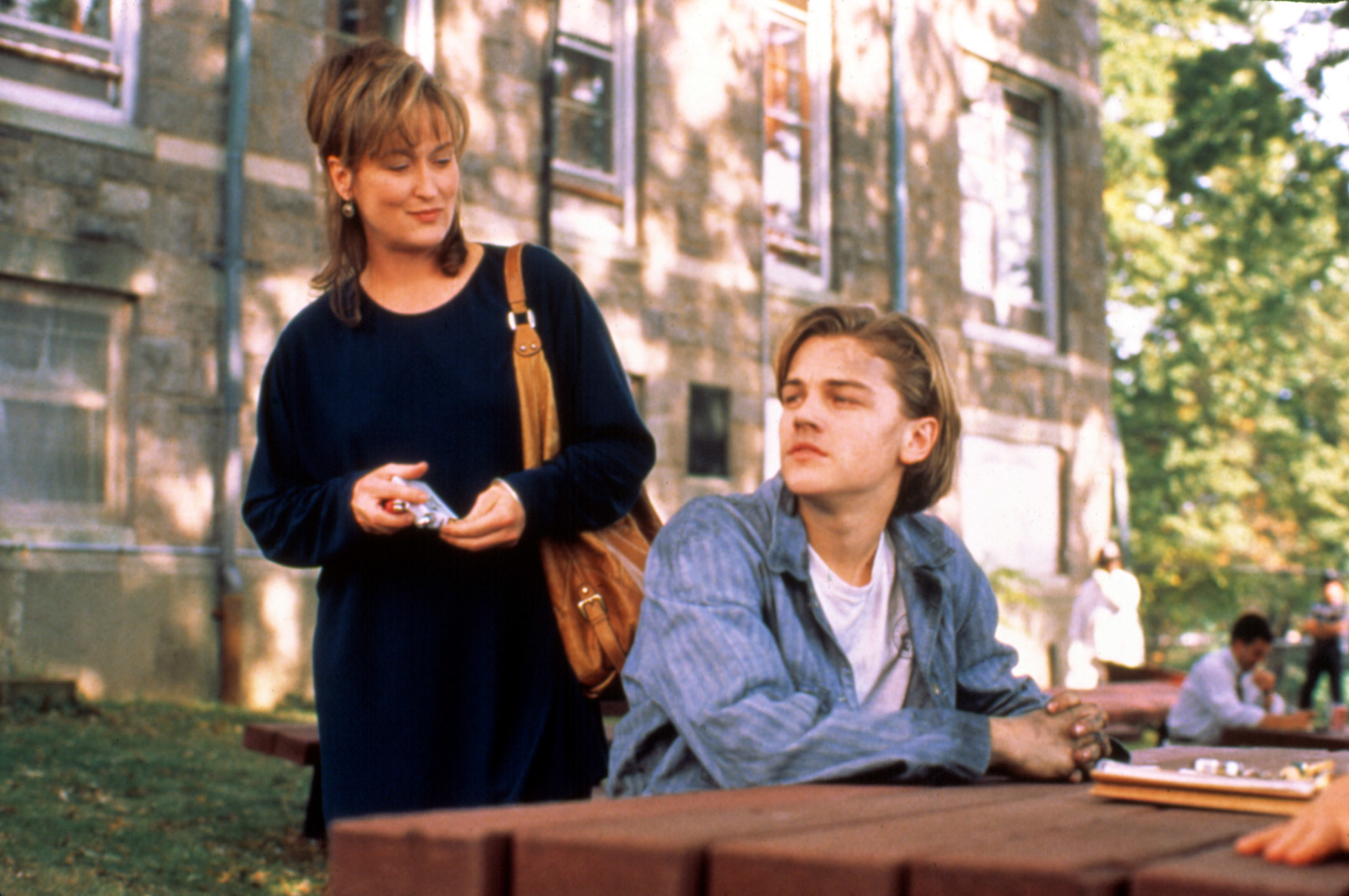 Meryl Streep stands behind Leonardo DiCaprio outside.