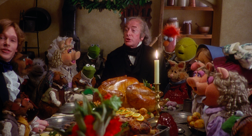 Scrooge sitting at the dinner table with the muppets