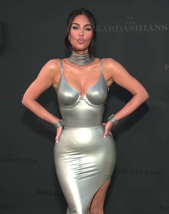 Kim Kardashian making a kiss expression with her hands on her hips as she poses for photographers at an event in a skin-tight dress