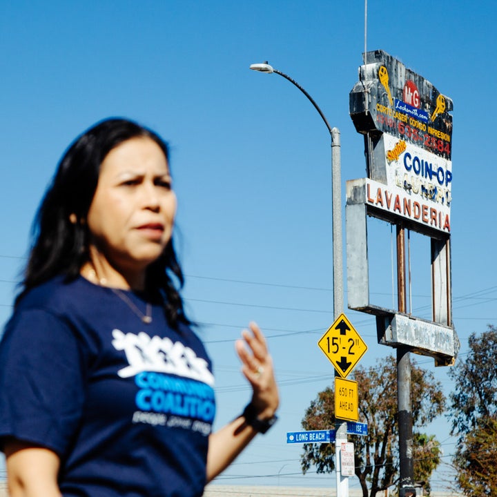 A woman speaks in front of a damaged sign