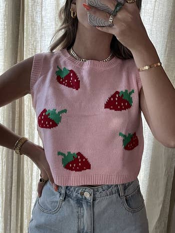 A reviewer wearing the pink strawberry sweater