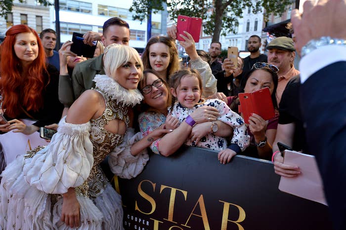 Lady Gaga posing with fans on a red carpet