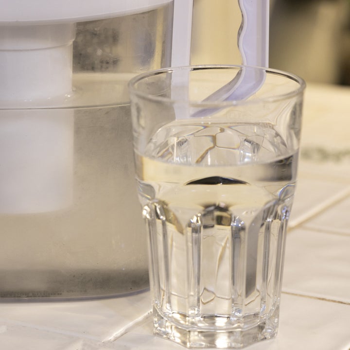 A glass of water standing next to a water filter