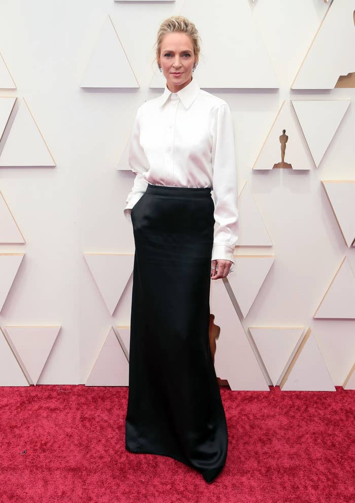 Uma Thurman attends the 94th Annual Academy Awards at Hollywood and Highland on March 27, 2022 in Hollywood, California. She wears a white shirt tucked into a black, silky fitted skirt which flows to the floor