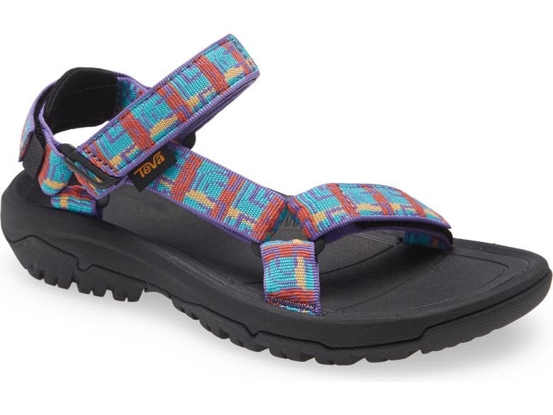 a teva sandal with a rubber grippy sole and a red and blue abstract pattern on the straps