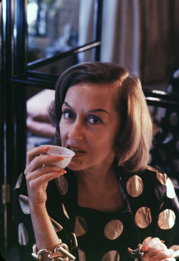 Gloria Swanson drinking from a small cup and looking at the camera