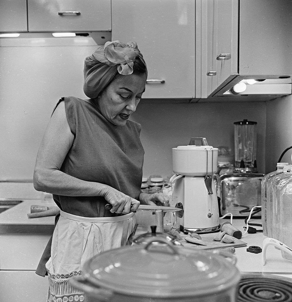 Gloria Swanson cutting veggies in the kitchen