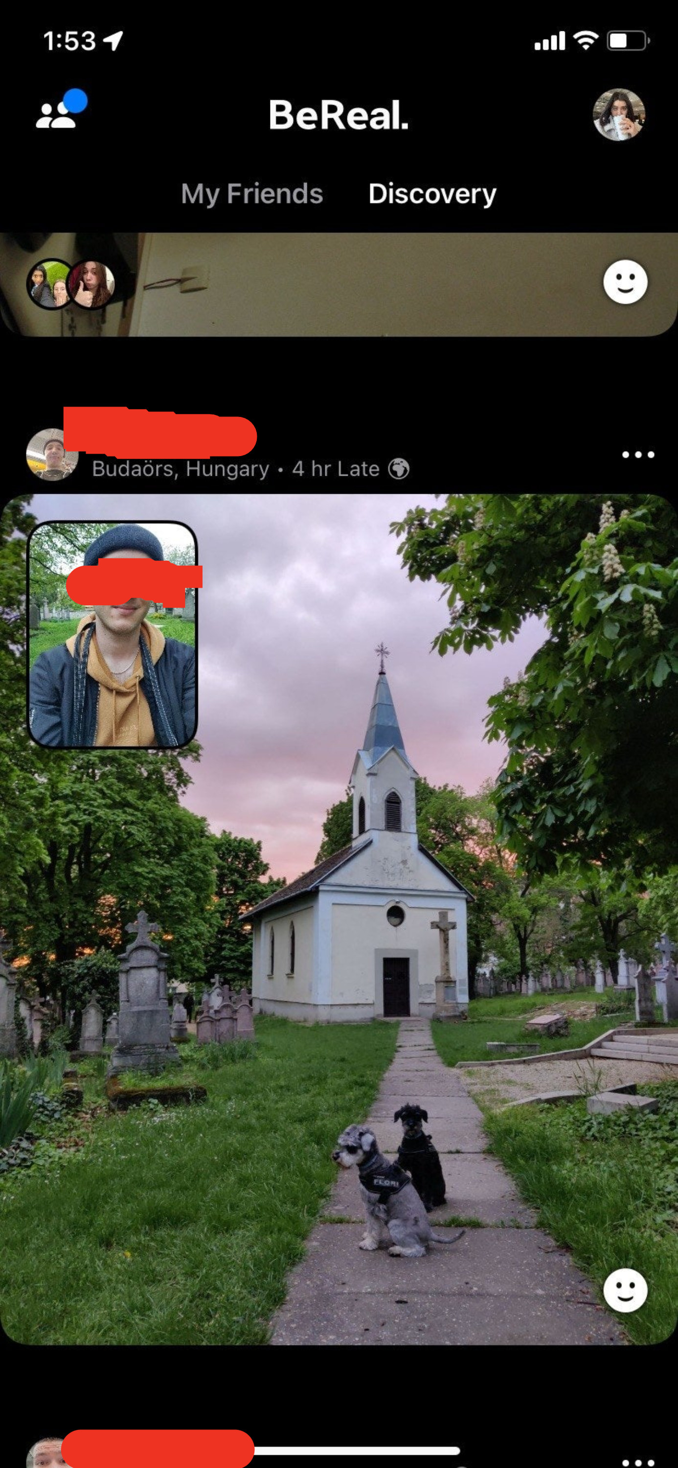 A man with two dogs in front of a church and cemetery