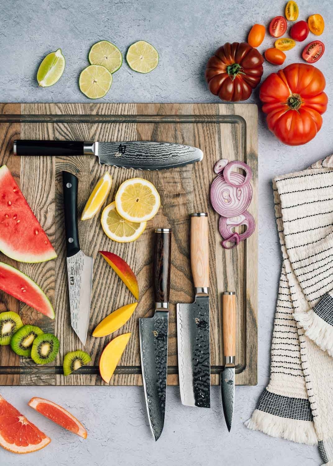 Cutting board with fruits and vegetables along with five different knives