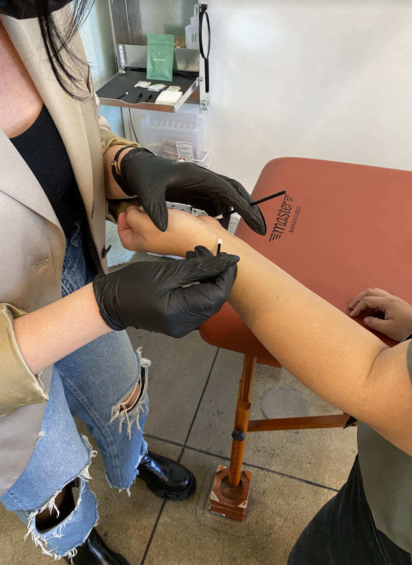 A shot of the brow artist performing a patch test on Crystal&#x27;s forearm