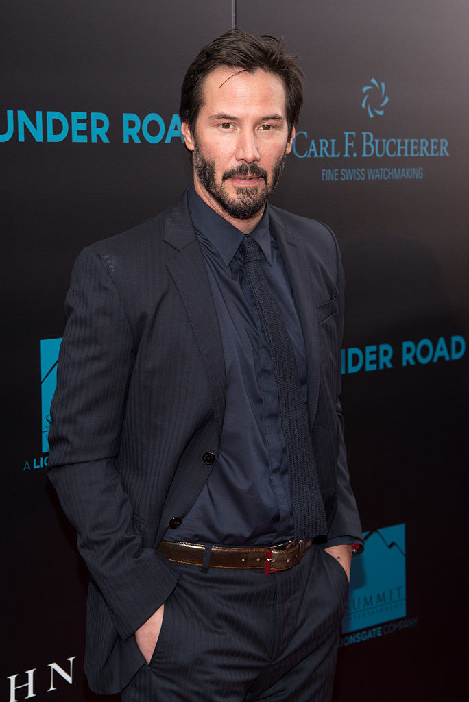 Keanu in a suit and tie with beard and mustache