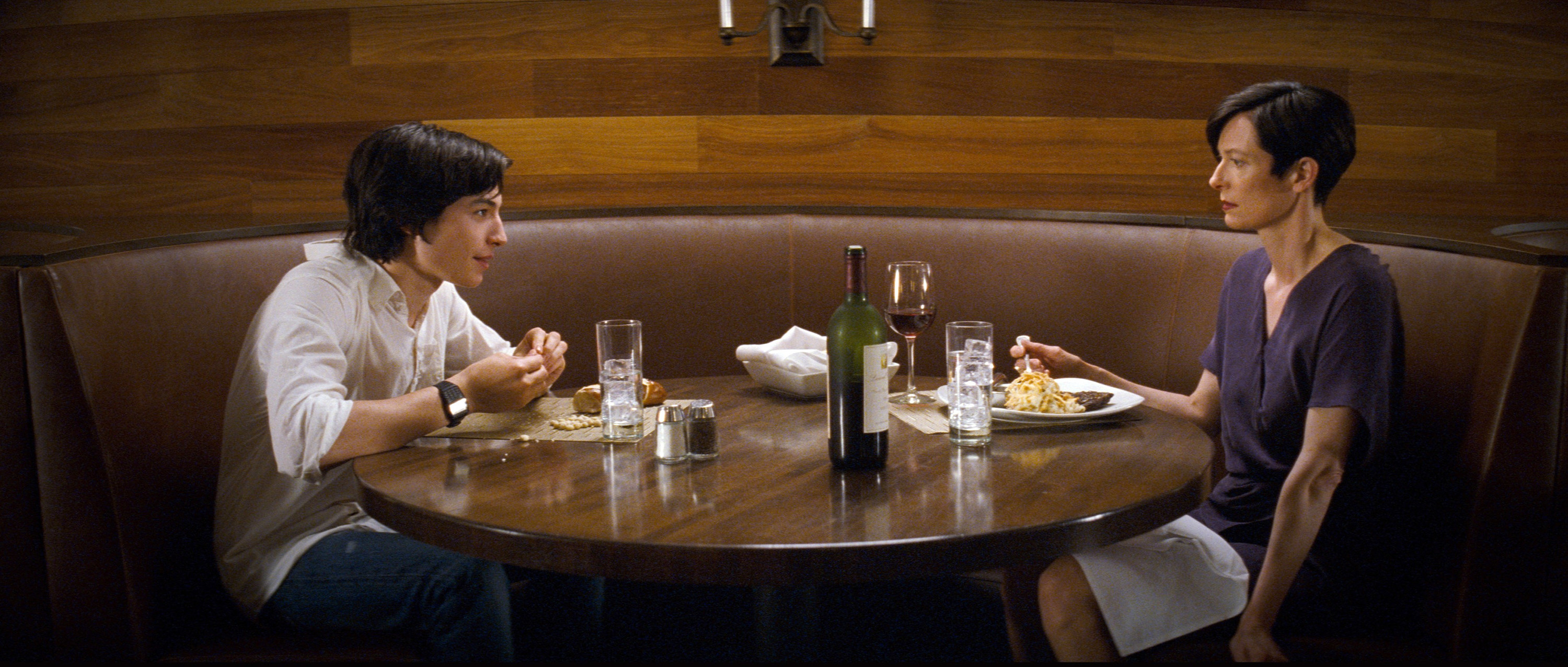 Ezra Miller and Tilda Swinton sit across a table