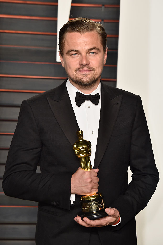 Leo holding an award, wearing a bow tie, and with a goatee and mustache