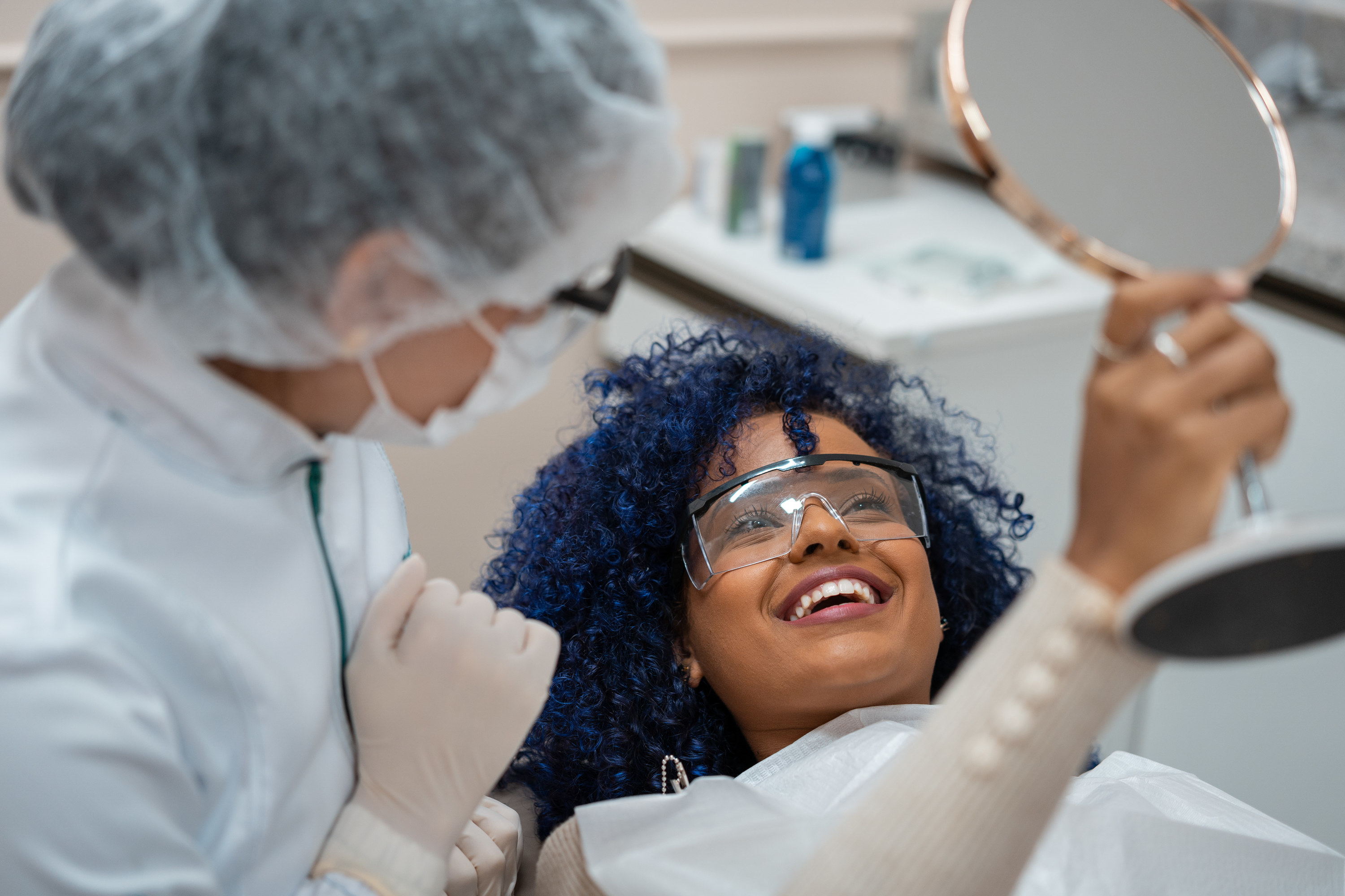 A person in a dentist's chair holding a mirror up