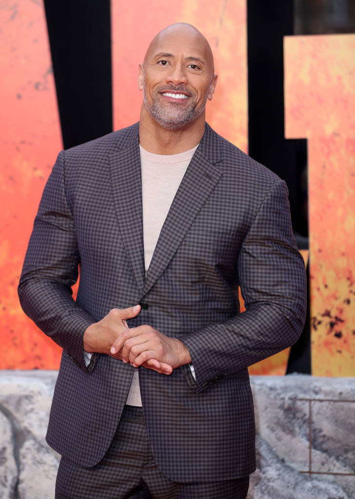 Smiling Dwayne in a suit with a short beard and mustache