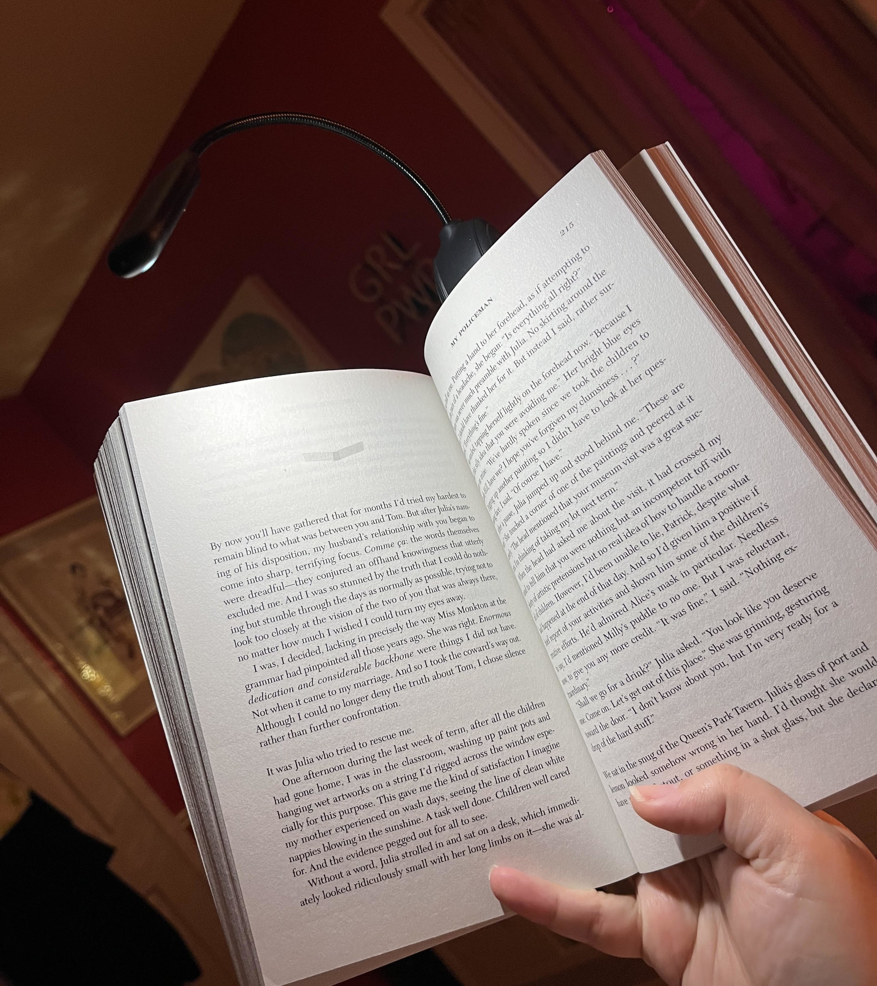 Bianca holding a book up with the light attached to the top as it illuminates the pages