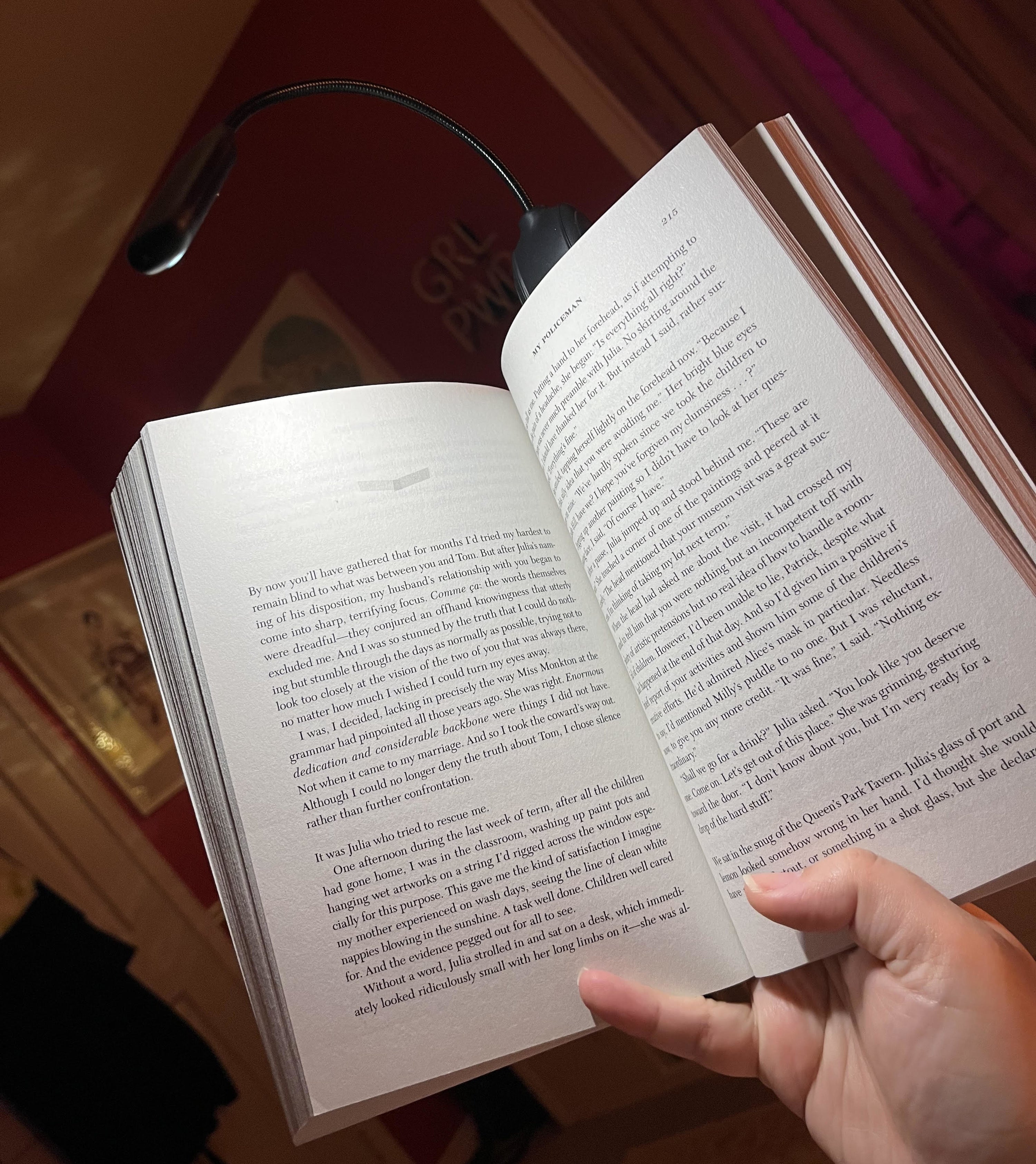 Bianca holding a book up with the light attached to the top as it illuminates the pages