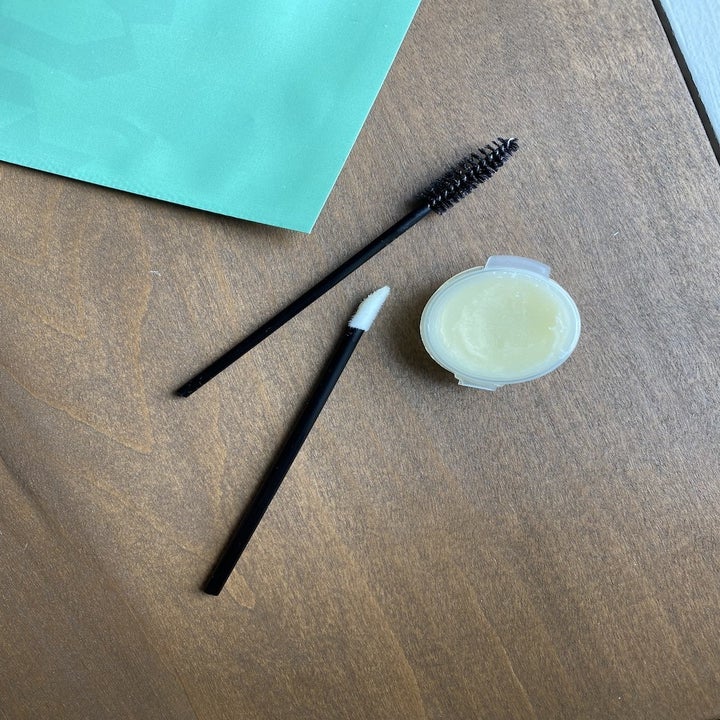 a spoolie brow brush, a brush with a sponge tip and a small container of ointment