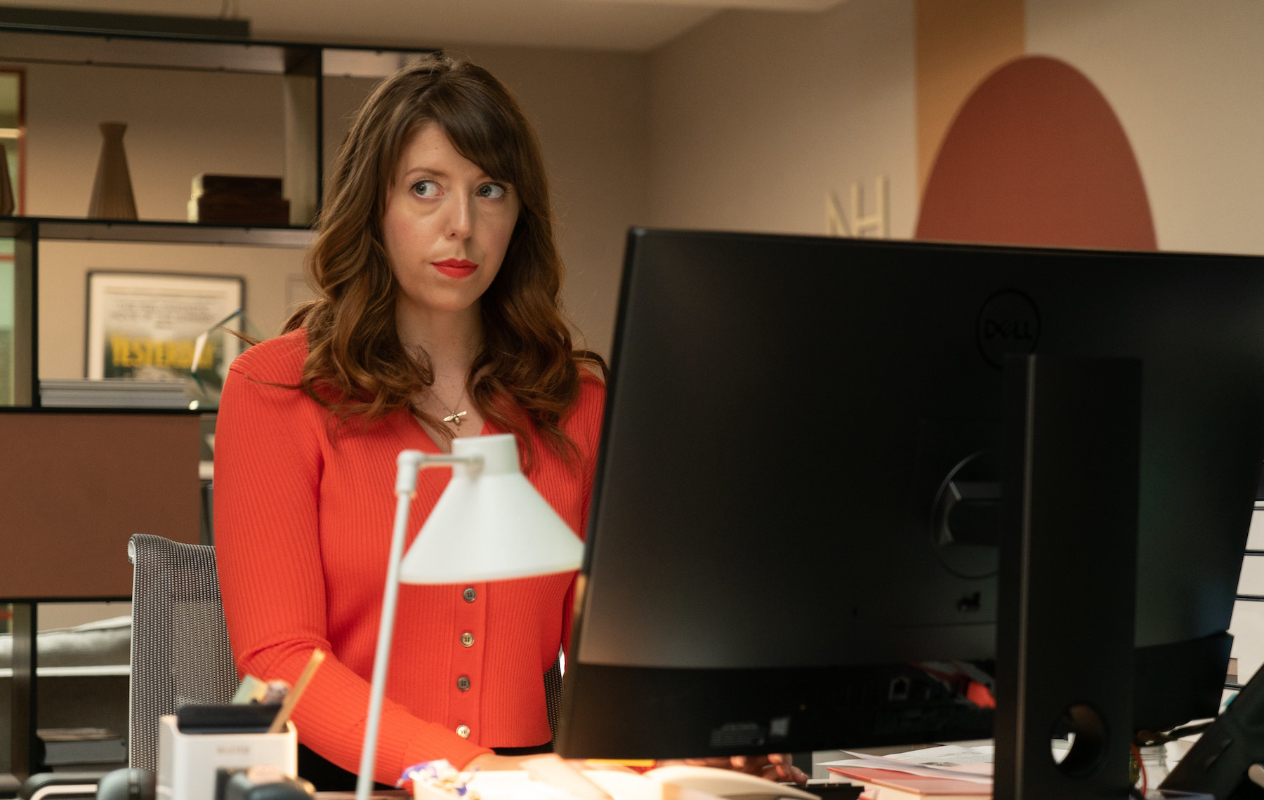 Rebecca as Julia sits at her desk in an office working at a computer and looking at something off screen