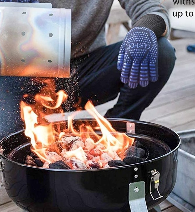 A person pouring something over a fire with the gloves on