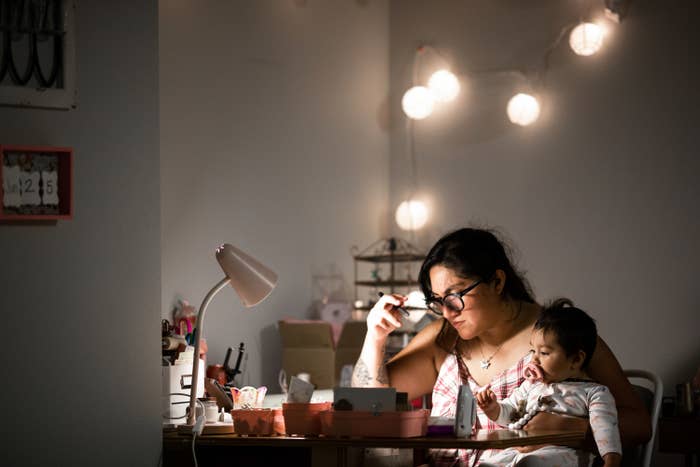 young woman holding her baby while working from home