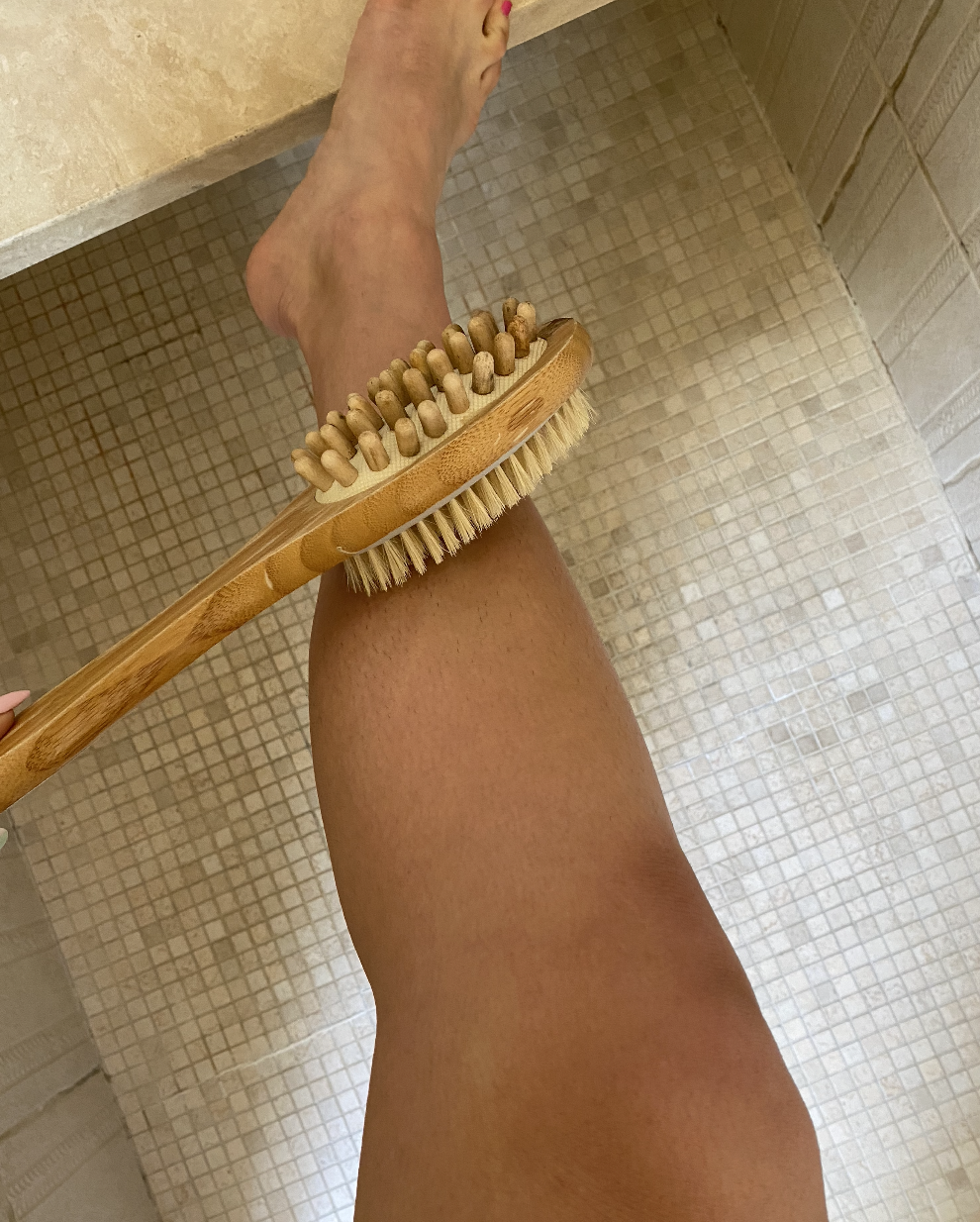 Author holding brush to her bare leg